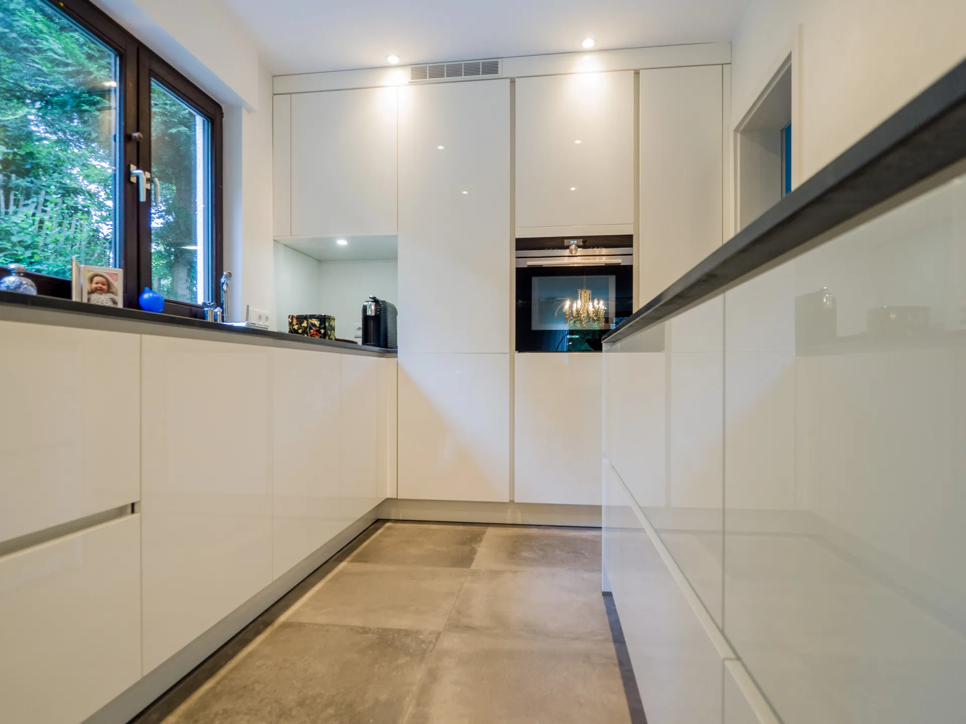 Designküche – Grifflose Hochglanz Küche in Weiß mit stilvoller Rückwand