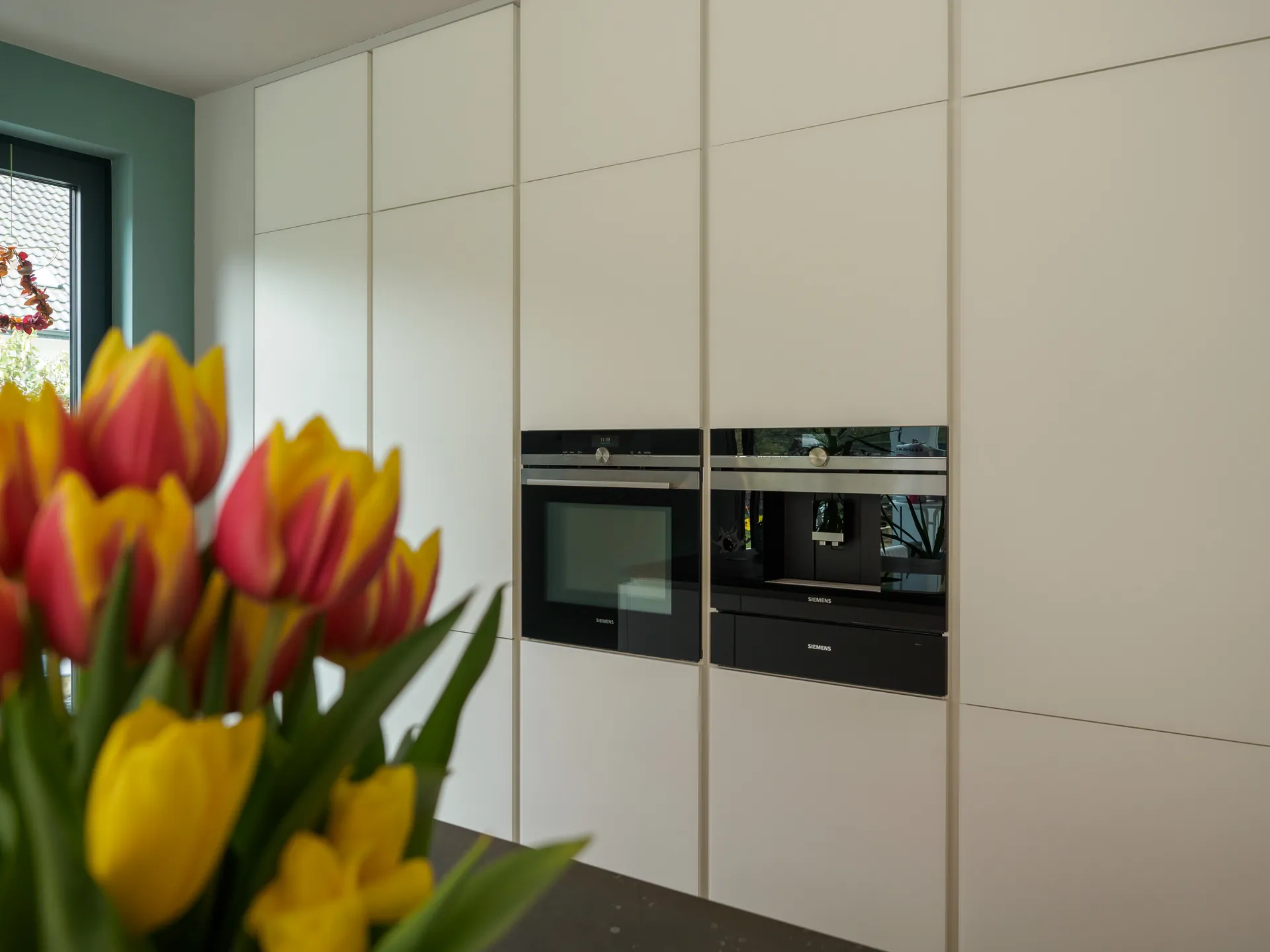Designküche mit Kochinsel – Grifflose Wohnküche mit großer Insel