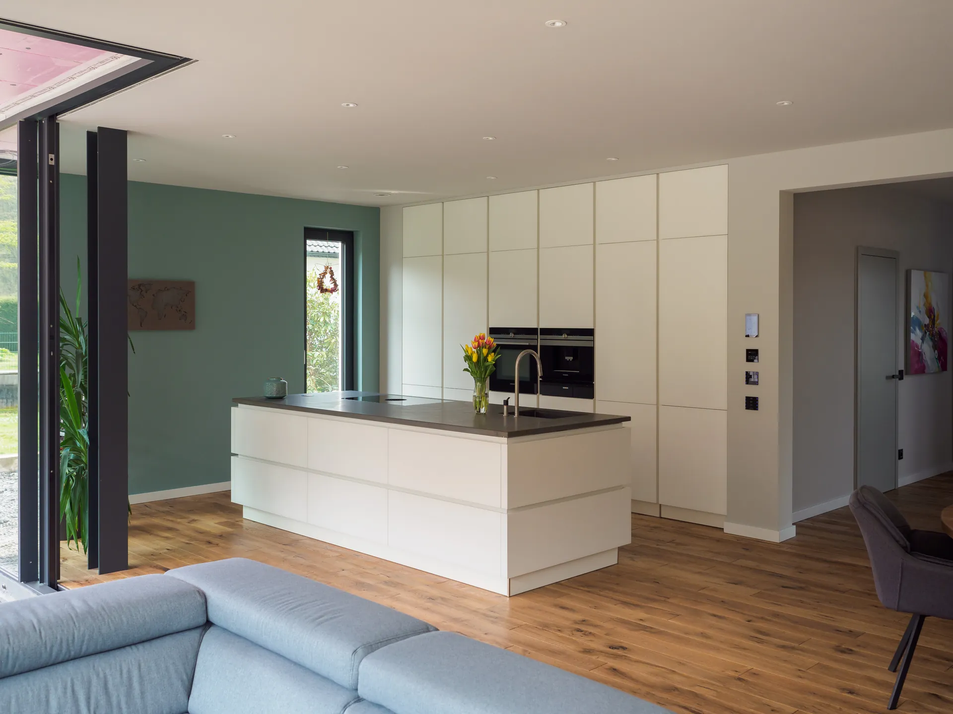 Designküche mit Kochinsel – Grifflose Wohnküche mit großer Insel