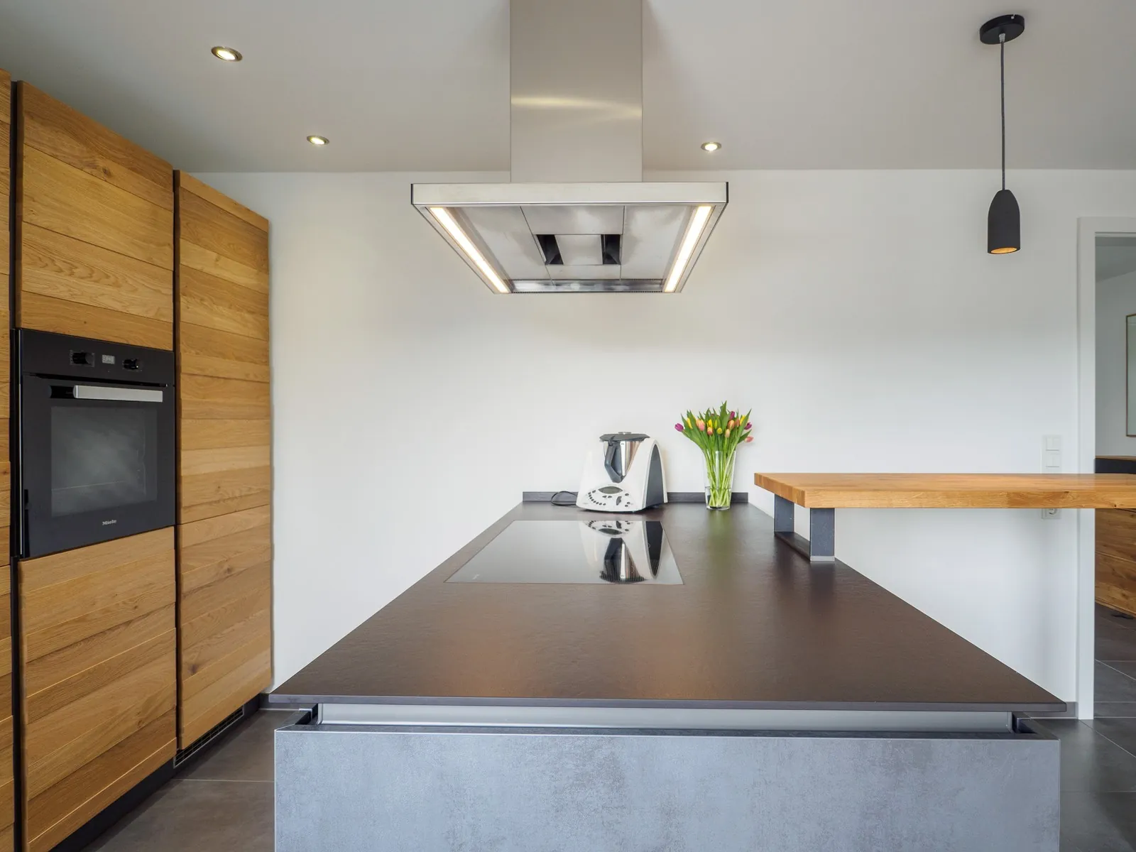 Grifflose Designküche mit Insel – Betonoptik mit Eiche und Dekton