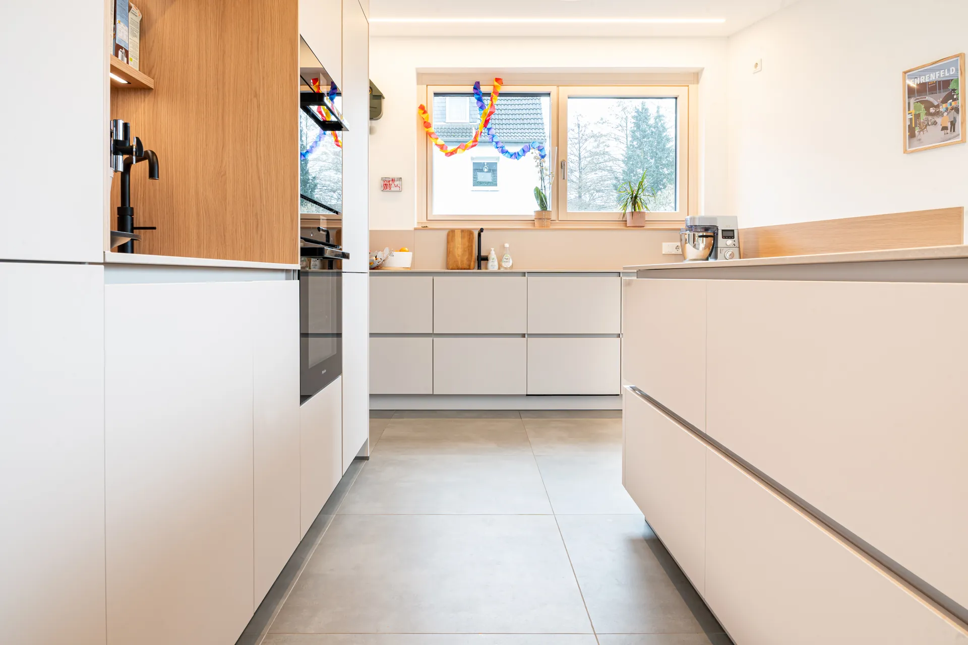Grifflose Designküche mit Insel – L-Form mit Holz und Keramik