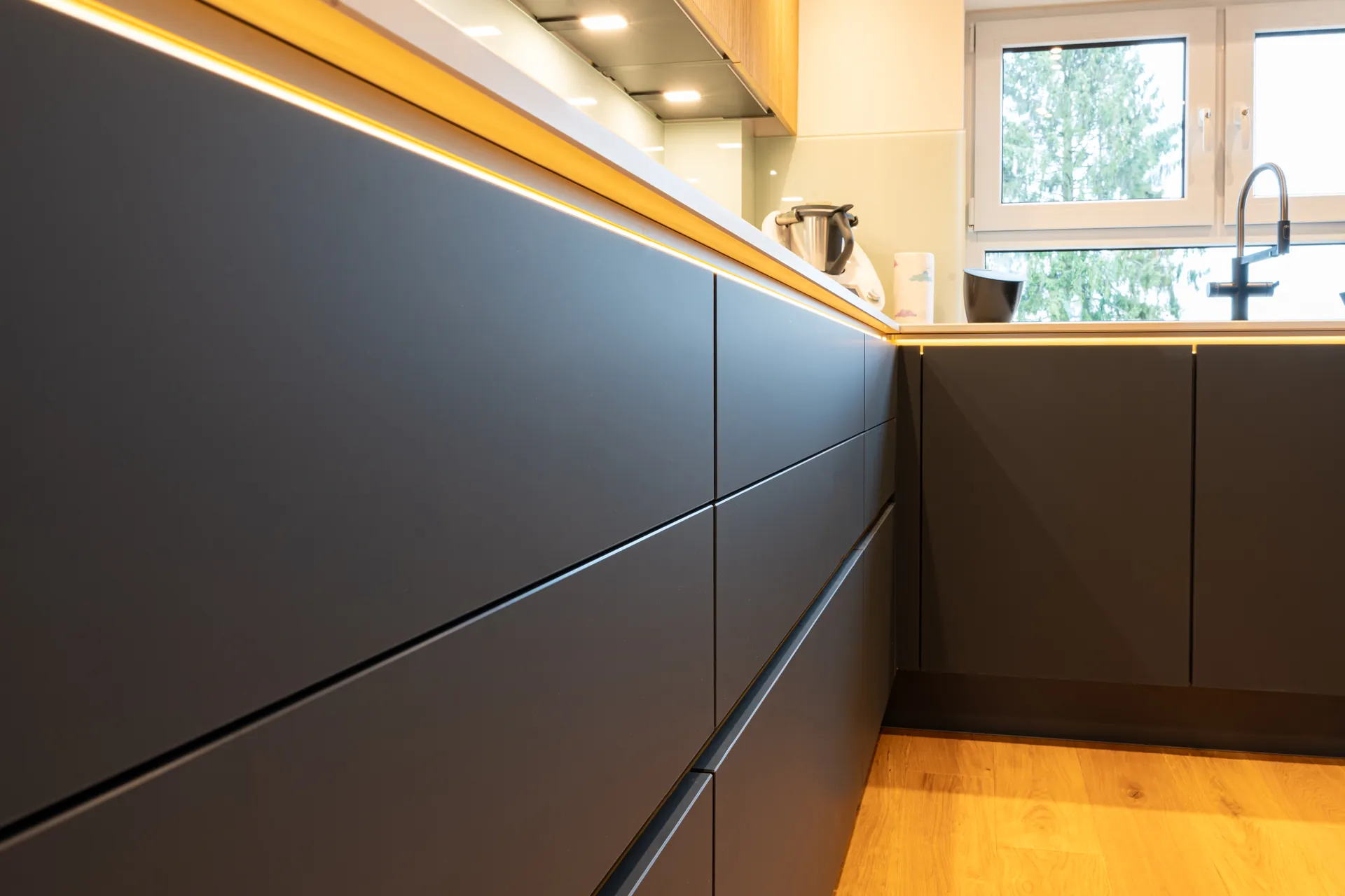 Grifflose Designküche in L-Form – Keramik und Holz mit Siemens