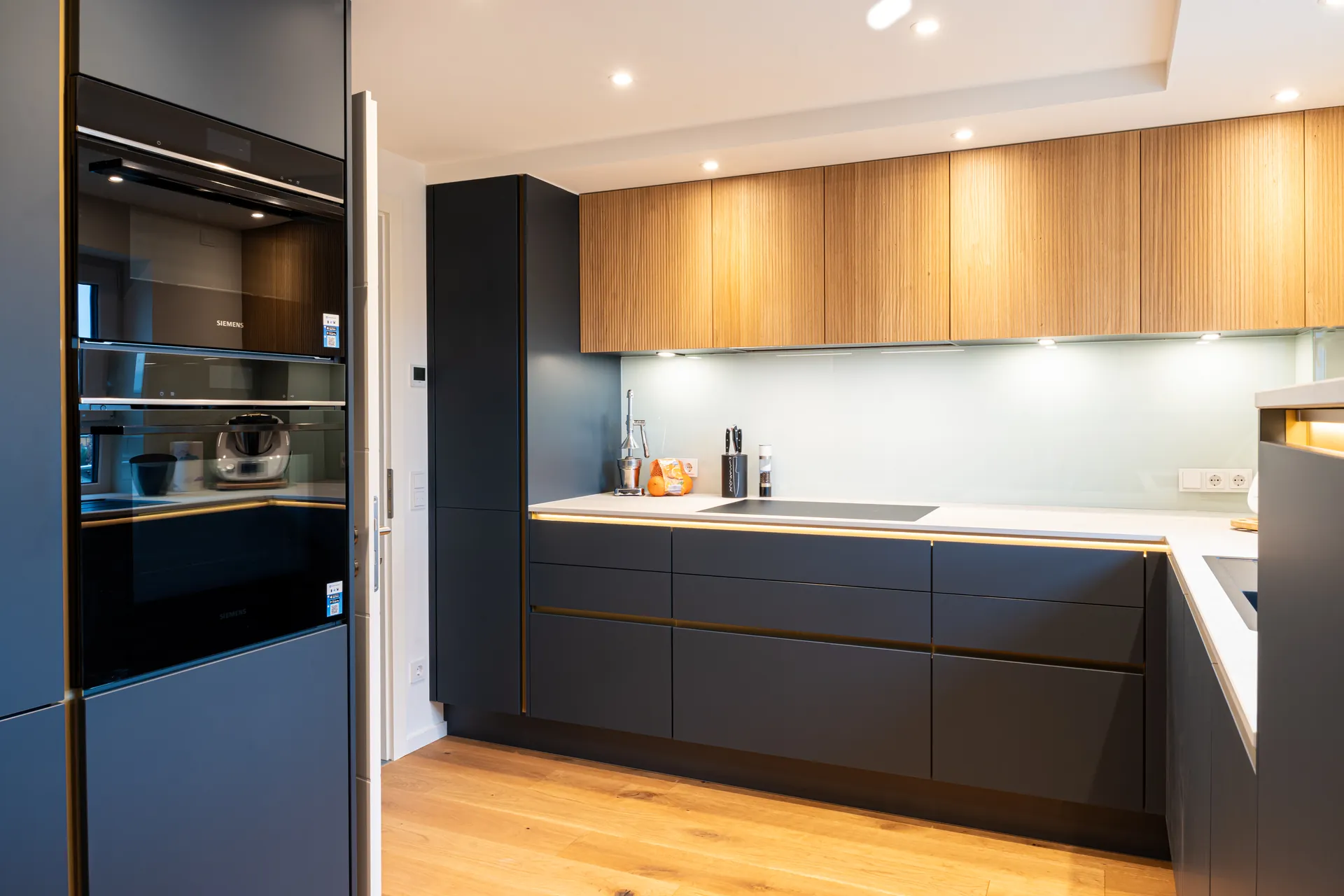Grifflose Designküche in L-Form – Keramik und Holz mit Siemens