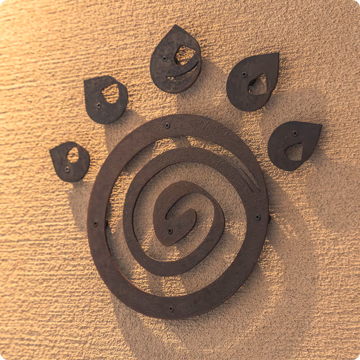 Metal artwork of a stylized paw print with a spiral center and five teardrop-shaped toes mounted on a textured wall.