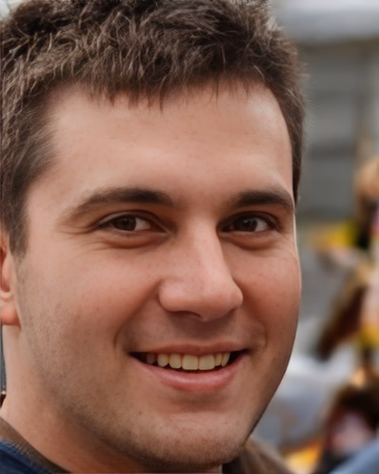 Close-up of a smiling young man with short brown hair and brown eyes.