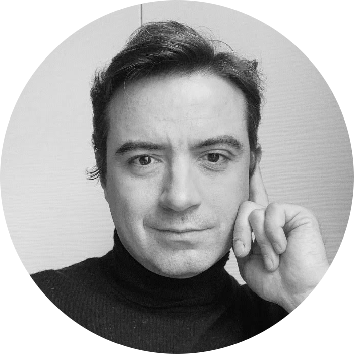 Black-and-white portrait of a man with short hair wearing a dark turtleneck, resting his head on his hand.