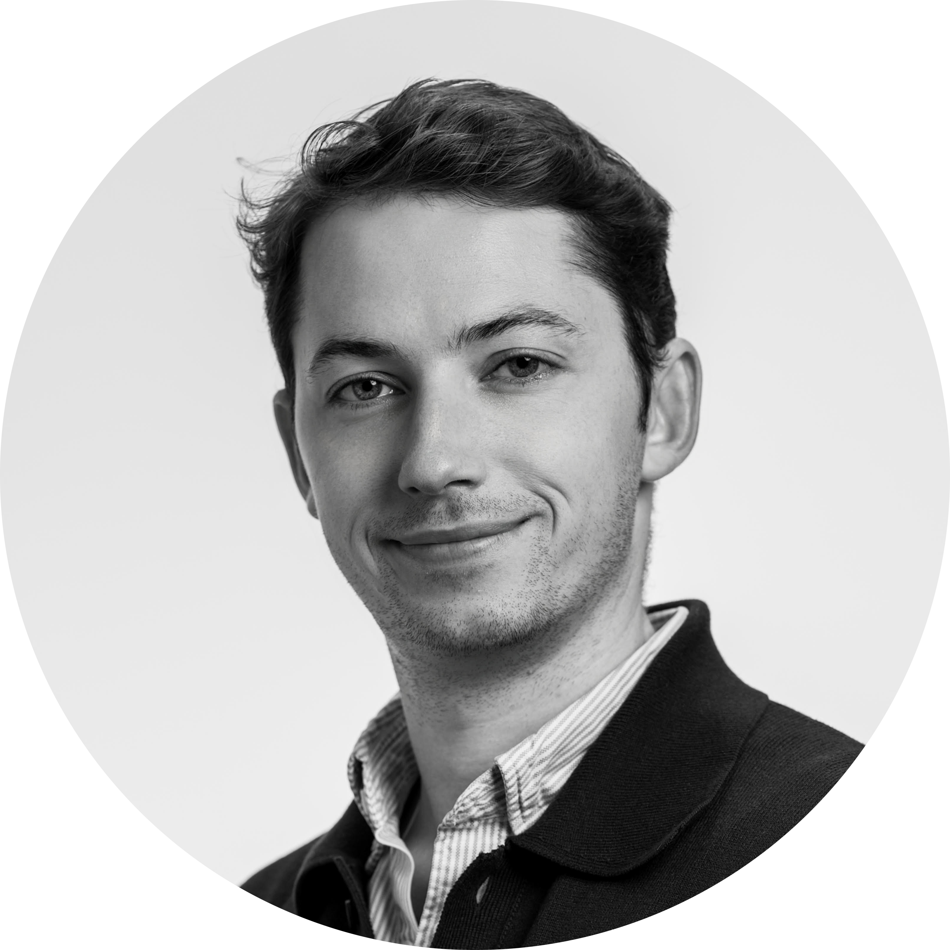 Black-and-white portrait of a smiling young man with short hair wearing a collared shirt and jacket.