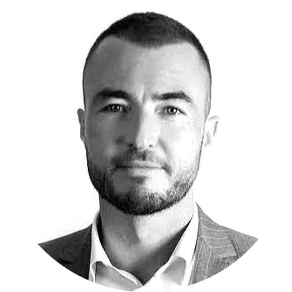 Black and white portrait of a man with short hair, trimmed beard, wearing a suit jacket and an open-collar shirt.