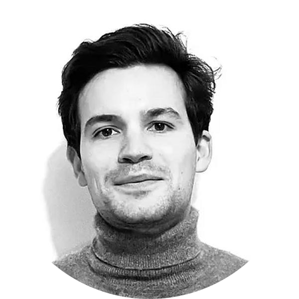 Black and white portrait of a man with dark hair wearing a turtleneck sweater, smiling slightly against a plain background.