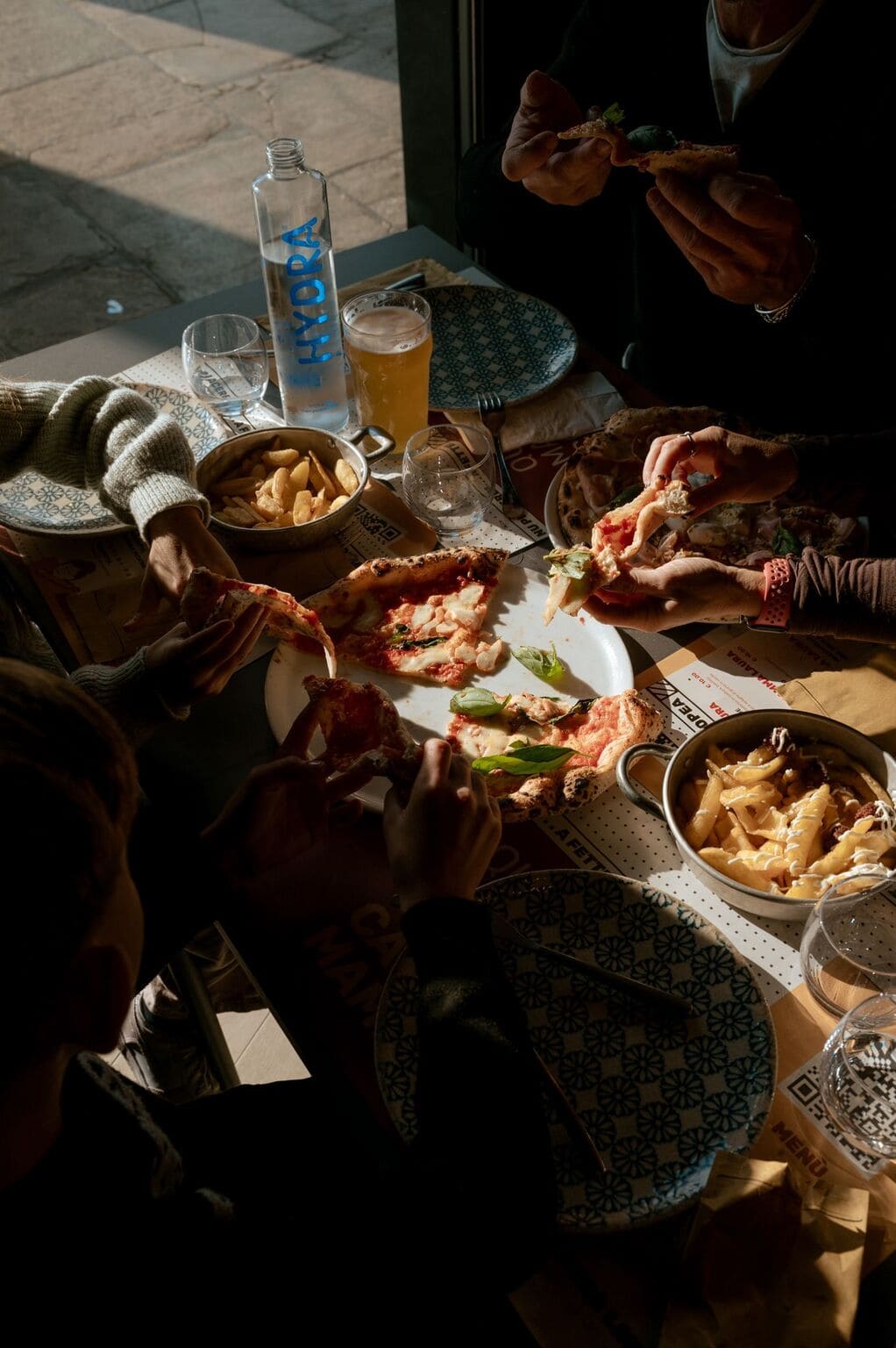 Two friends laughing and having pizza at table