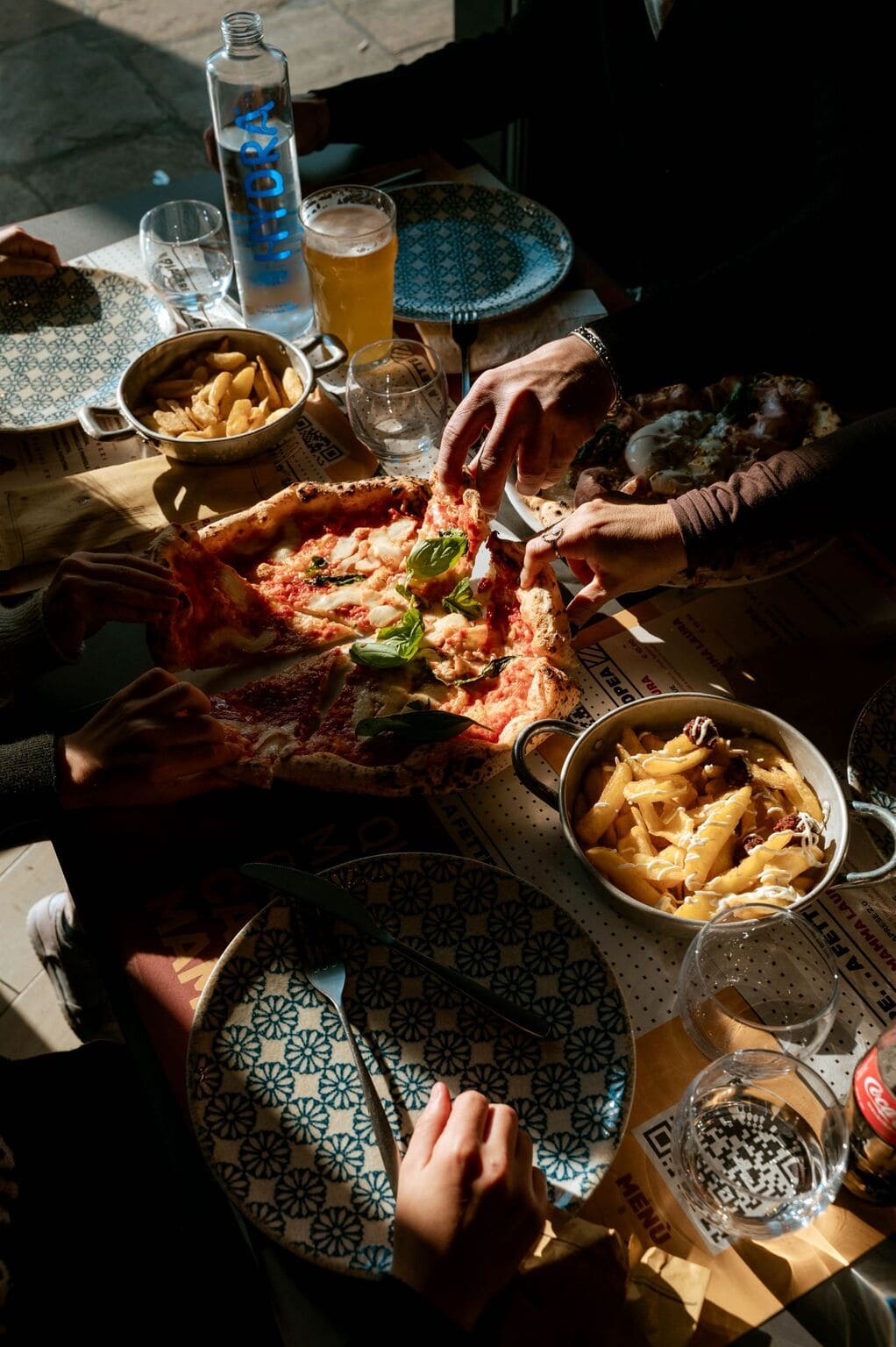 A little boy eating a big pizza and drinking water