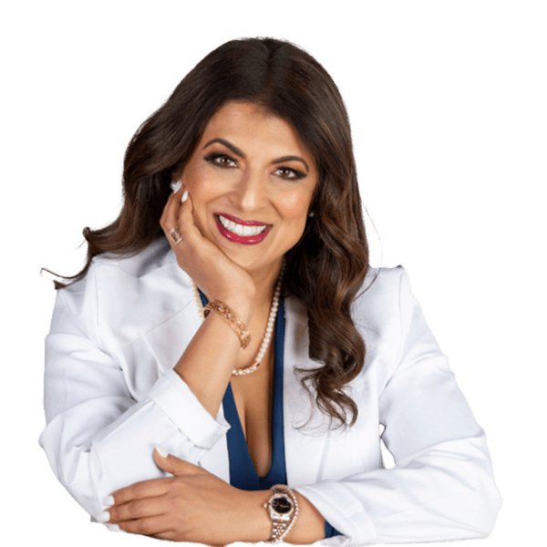 Smiling woman with long brown hair wearing a white blazer, blue top, pearl necklace, and wristwatch, resting her face on one hand.