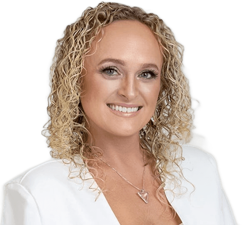 Smiling woman with curly blonde hair wearing a white top and a triangular pendant necklace.