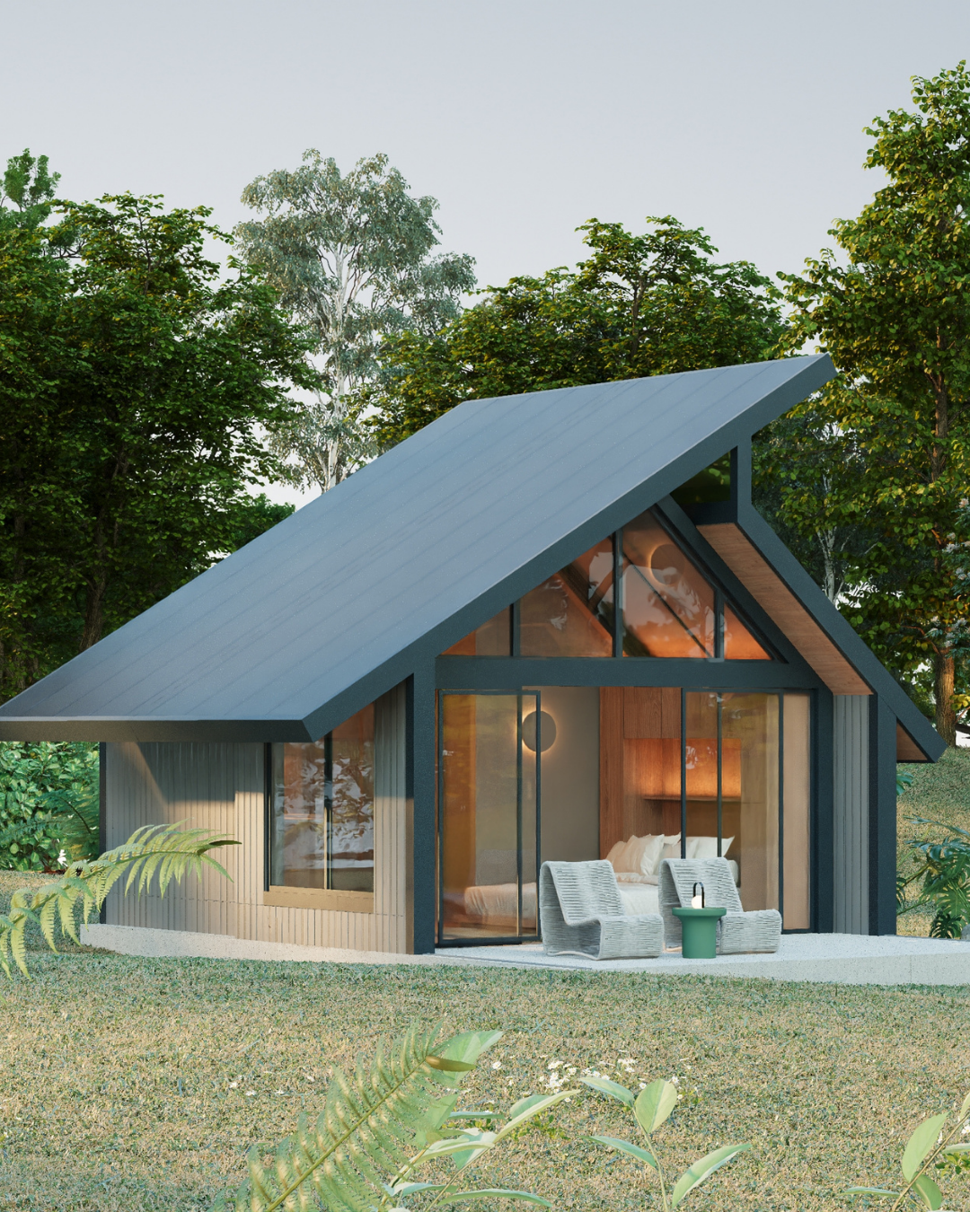 Casa moderna pequeña con techo inclinado y muebles en el patio, rodeada de árboles verdes.