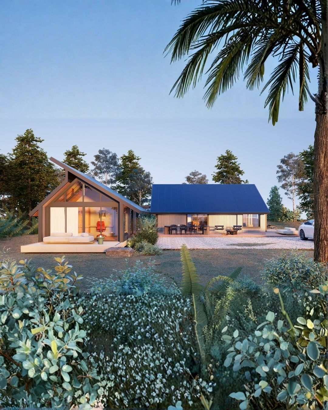 Casa moderna con techo azul y jardín verde rodeado de árboles y plantas, al atardecer.