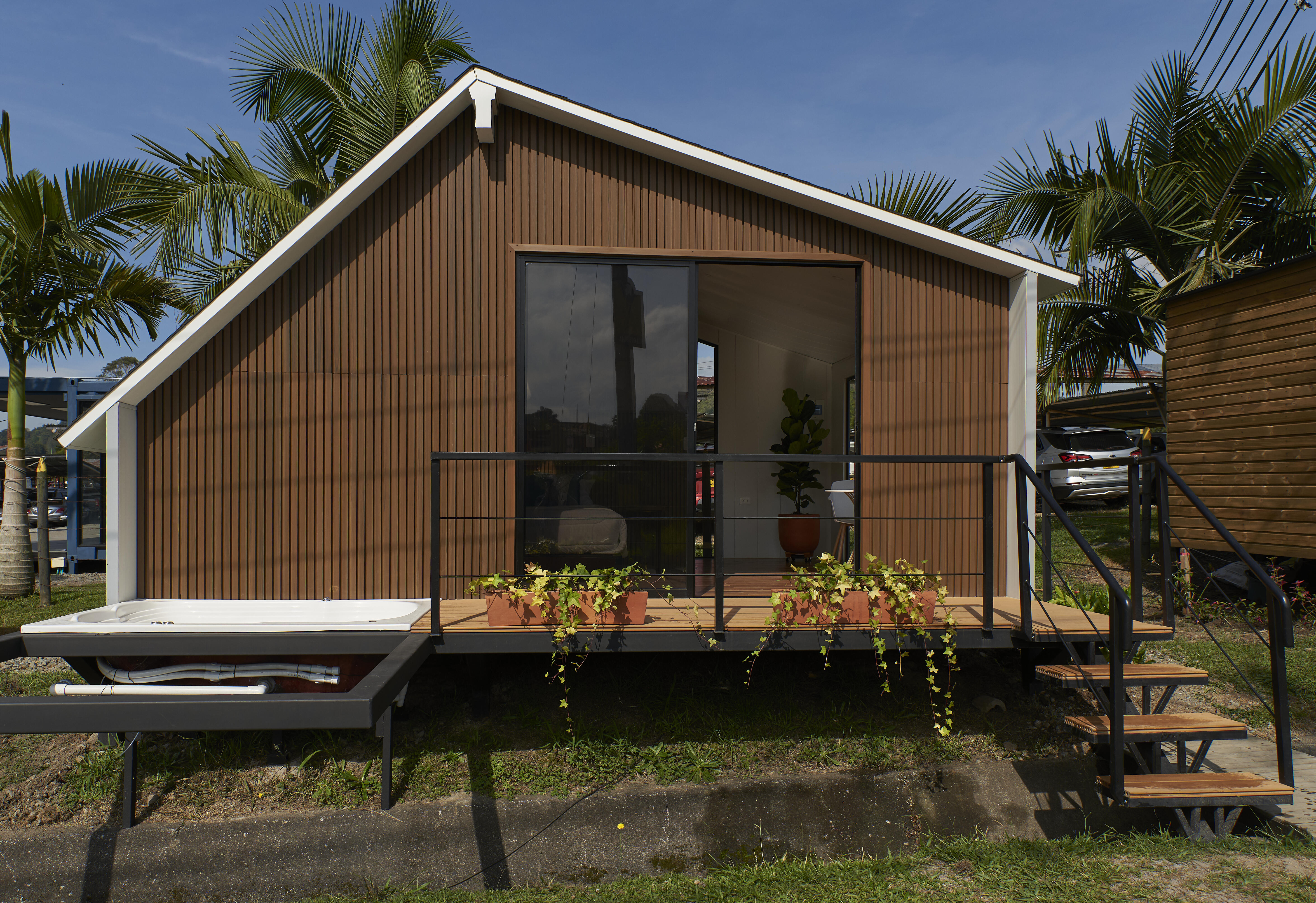 Casa con fachada marrón, terraza con plantas y jacuzzi al aire libre con escalera negra.