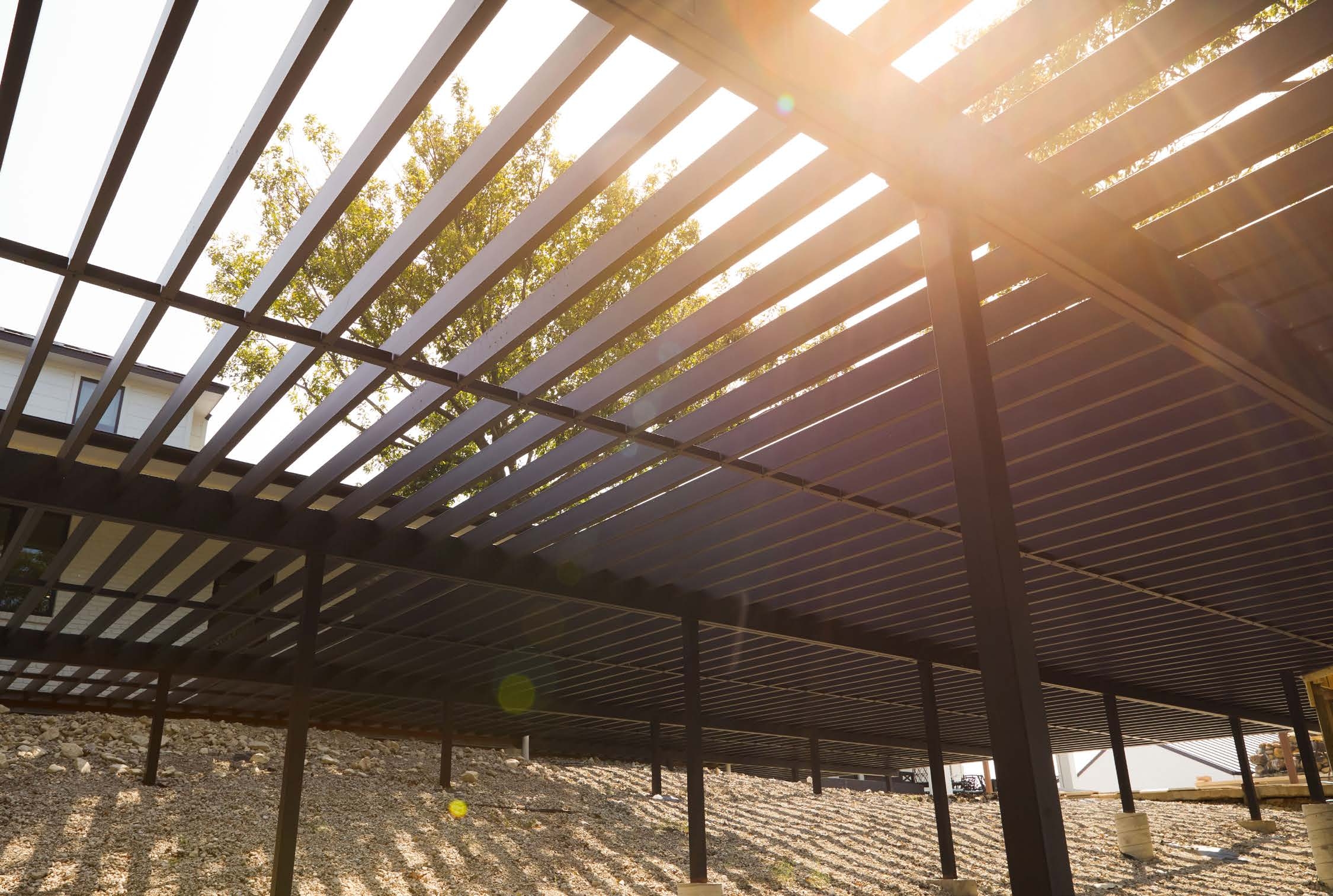 Estructura metálica para deck instalada sobre tierra con luz solar y árboles detrás.