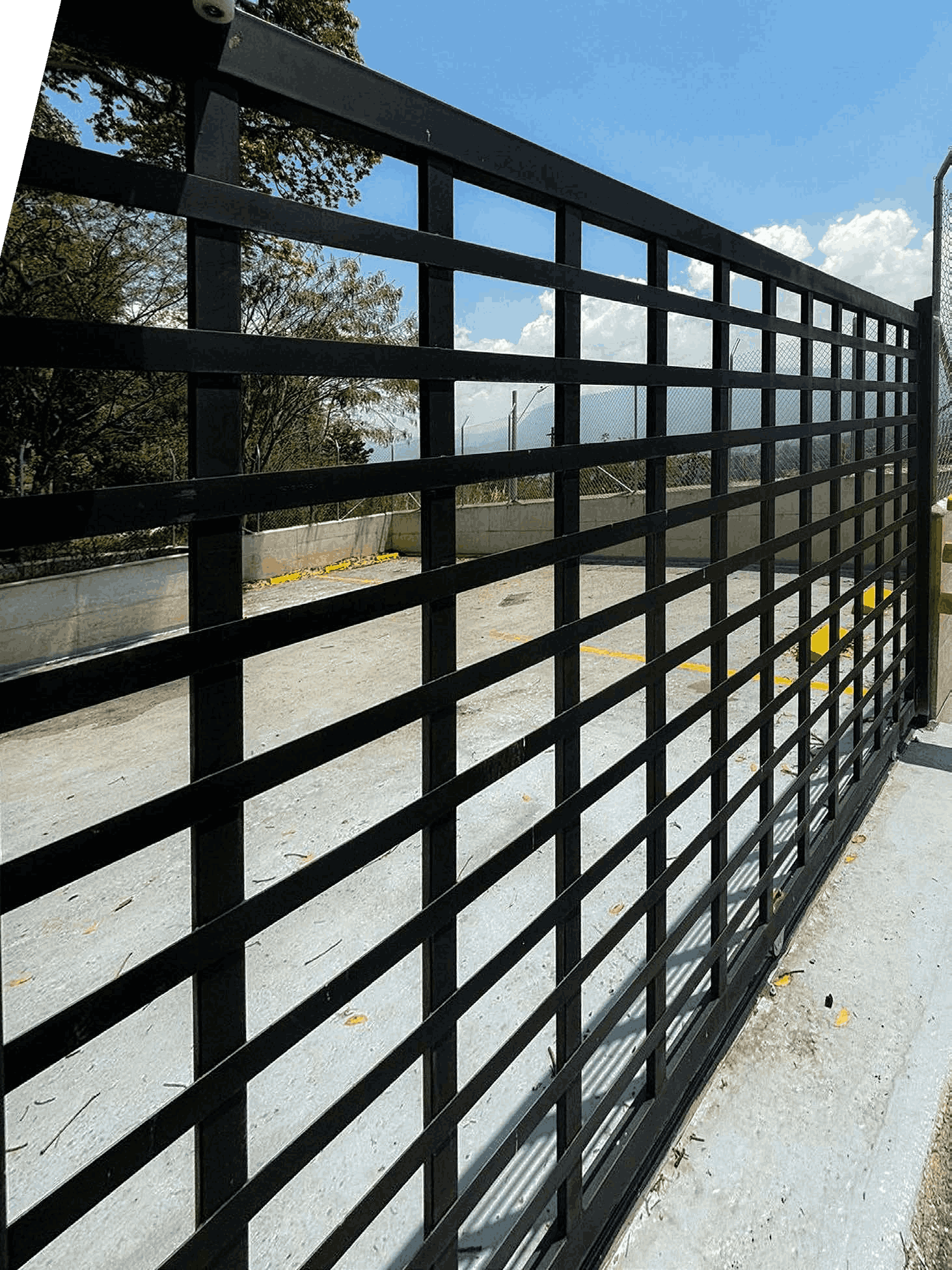 Reja de metal negra con diseño cuadriculado en un área exterior con cielo azul.