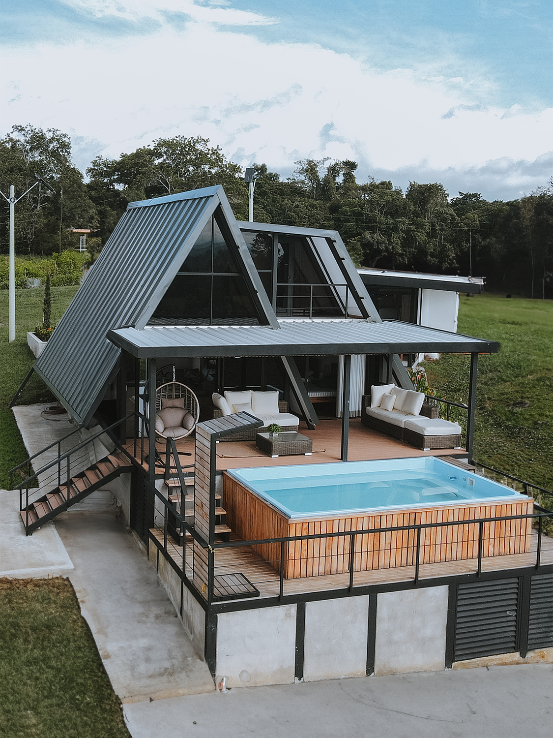 Casa moderna tipo cabaña con techo a dos aguas, terraza con piscina y muebles lounge.