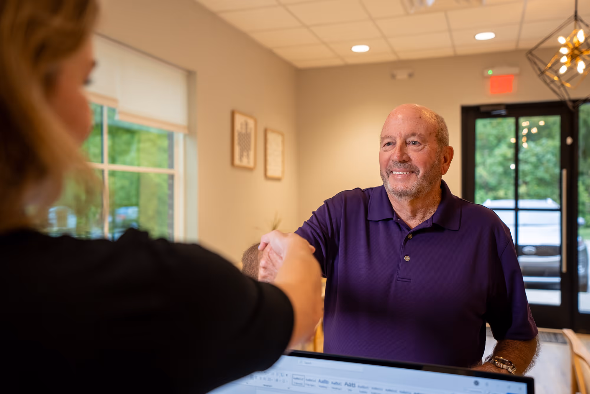 A man shaking hands with a woman in a room.