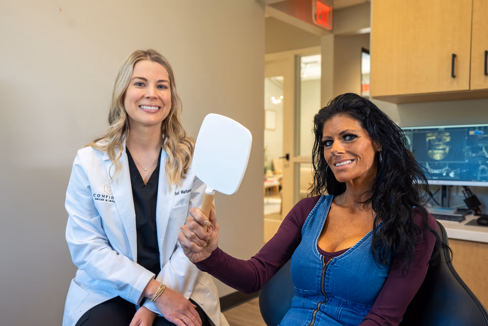A woman sitting in a chair holding a mirror.