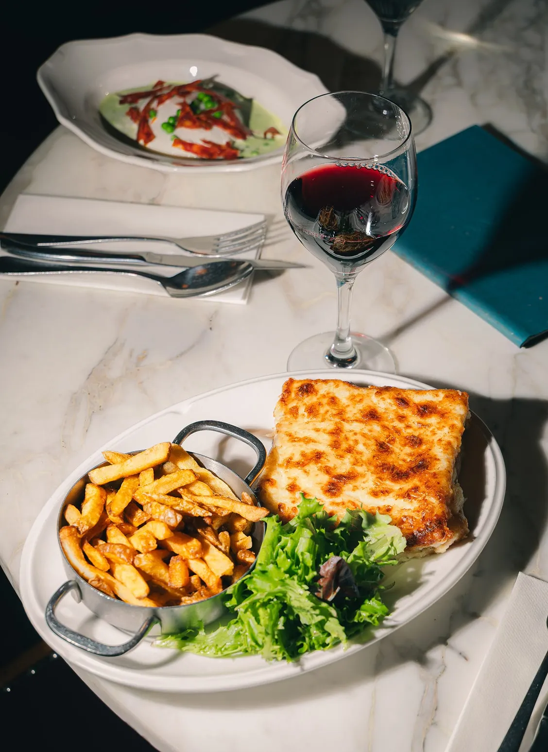 Plat de lasagnes maison accompagné de salade et de vin rouge