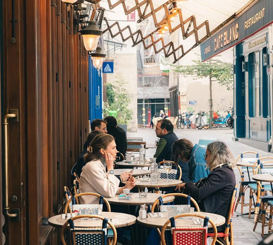 Clients dégustant un repas en terrasse du Café Blanc