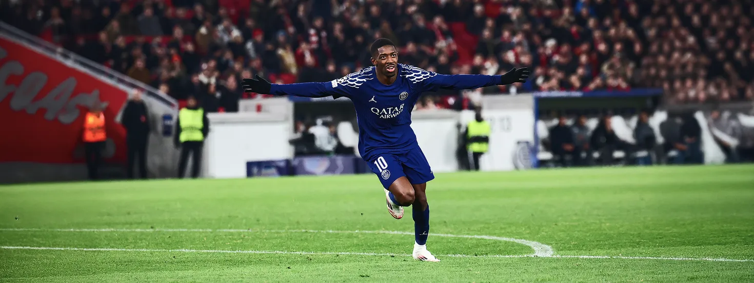 Soccer player in blue PSG jersey with number 10 celebrating on a green field with arms outstretched, spectators in background.