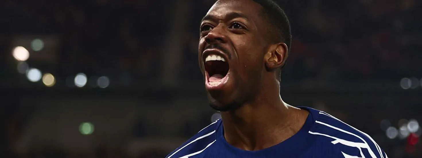 Close-up of a man in a blue sports jersey shouting energetically with a blurred dark background.