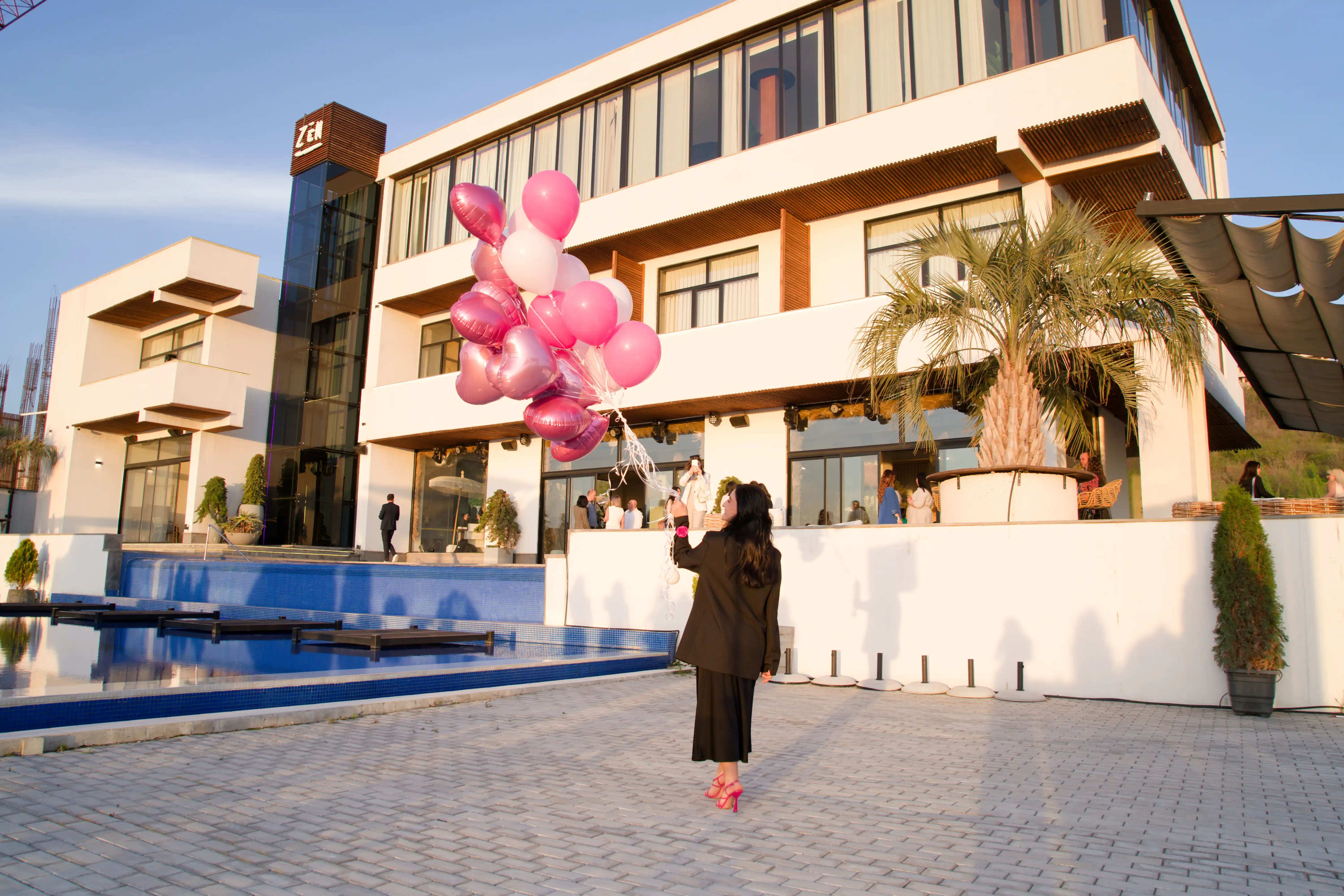 Family events package banner showing a woman holding pink heart balloons at a luxury outdoor venue for Perla Signature Events premium family celebration planning services in Yerevan, Armenia
