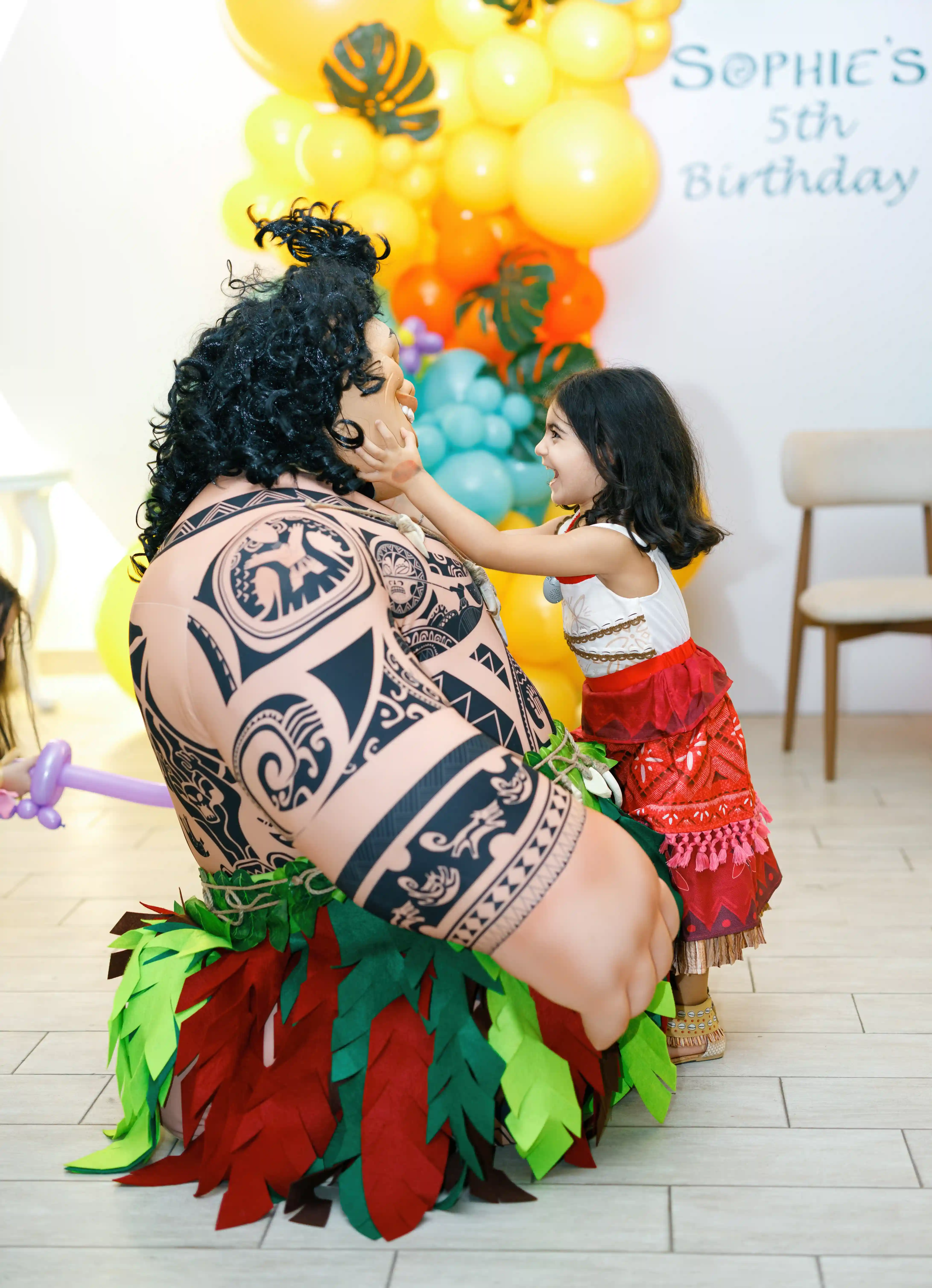 Birthday girl in a tropical island princess costume joyfully interacting with a professional Polynesian warrior character performer at a luxury themed fifth birthday party by Perla Signature Events in Yerevan, Armenia