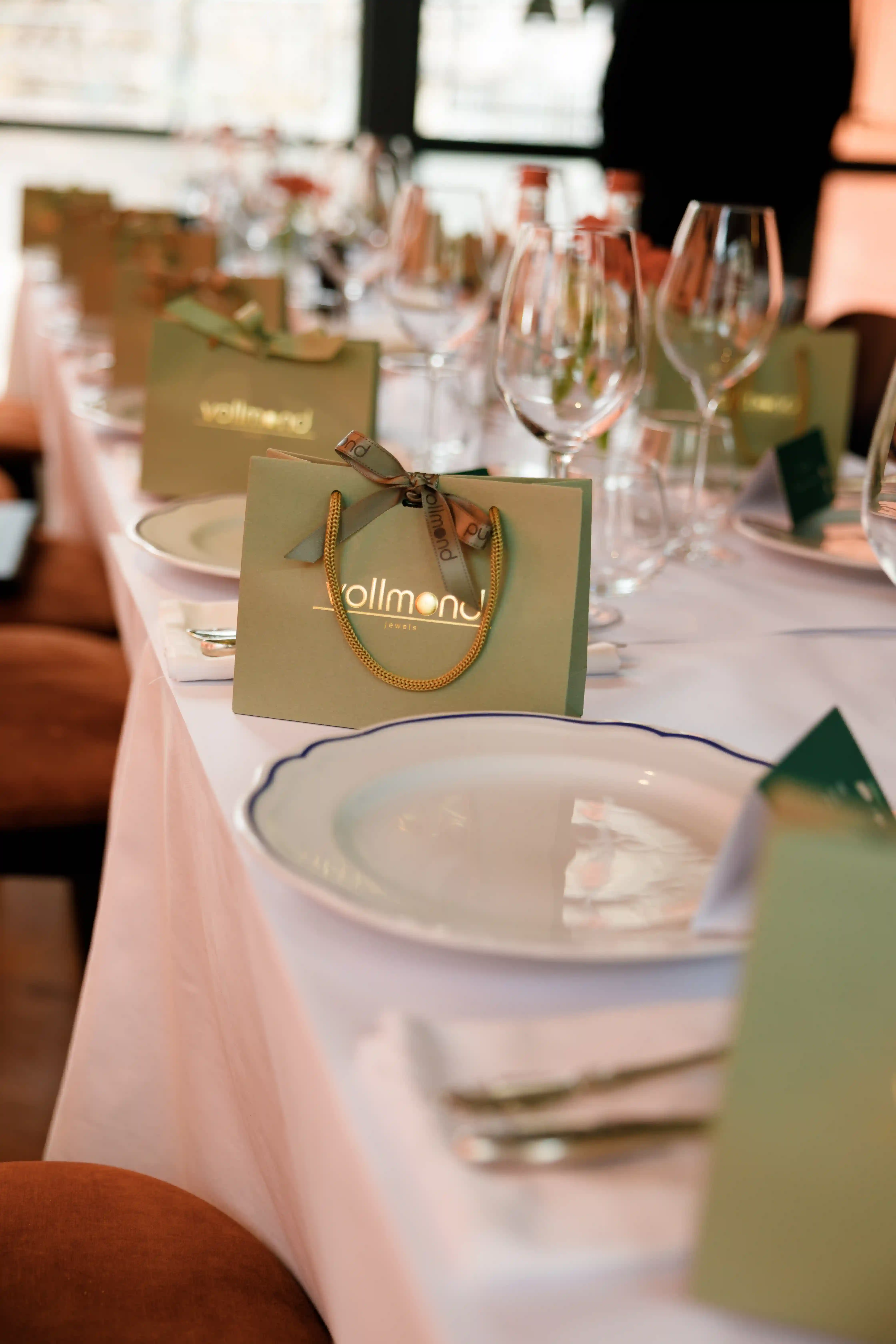 Elegantly set long dining table with crystal wine glasses, fine china plates, and branded gift bags at a luxury corporate event styled by Perla Signature Events in Yerevan, Armenia