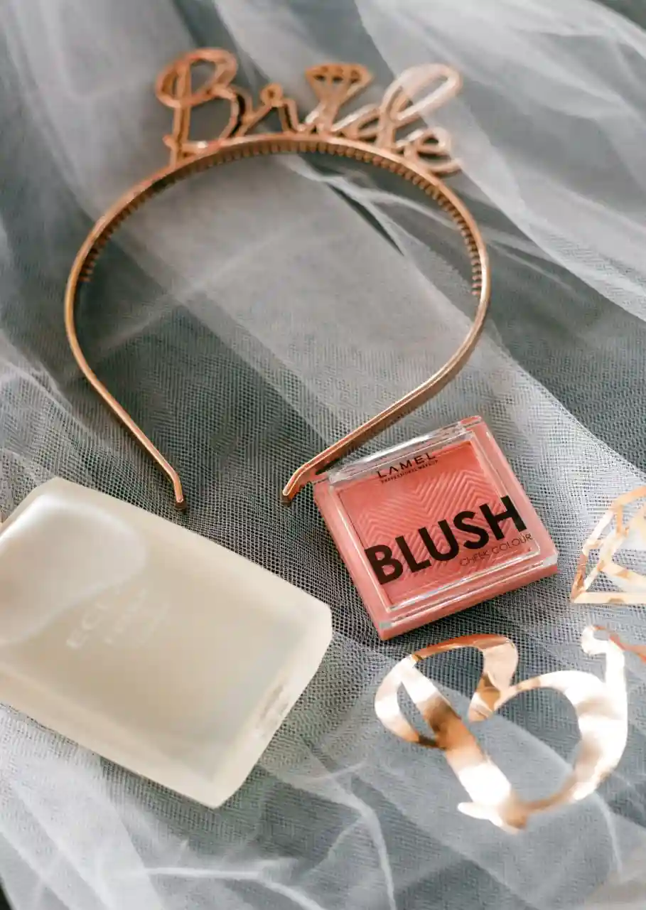 Rose gold bride tiara, blush compact, pearl soap and gold ribbon flat lay on grey tulle as luxury bachelorette party favor contents styled by Perla Signature Events in Yerevan, Armenia