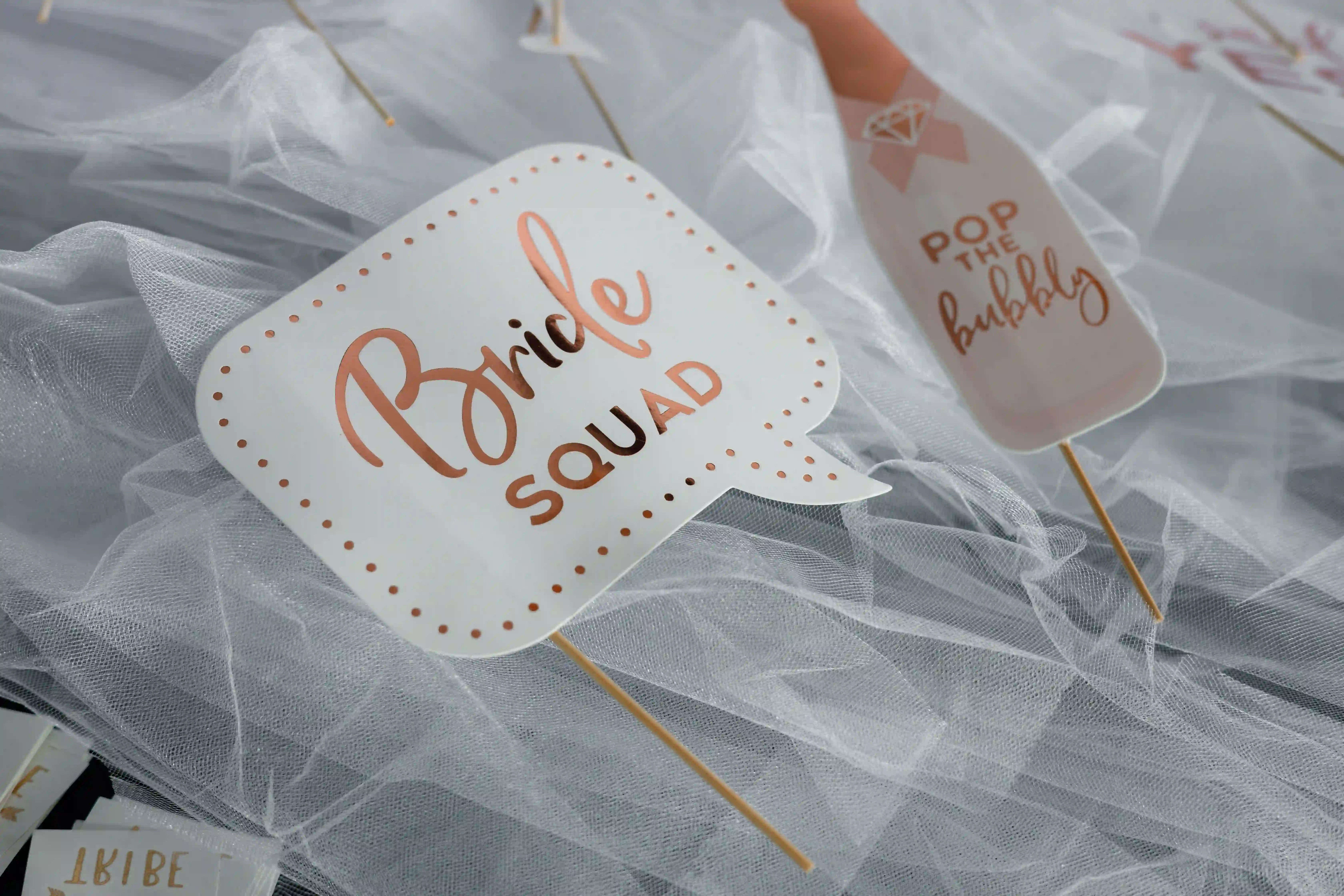 Rose gold `Bride Squad` and `Pop the Bubbly` photo booth props on white tulle at a luxury bachelorette party styled by Perla Signature Events in Yerevan, Armenia