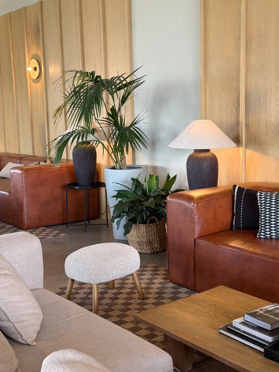 Lounge at Art Village with tan leather sofas, oak panelling and greenery