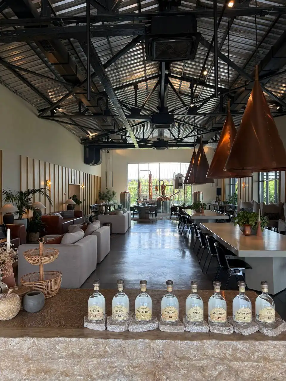 Distillery hall at Art Village with copper pendant lamps and local fruit spirits on the stone bar
