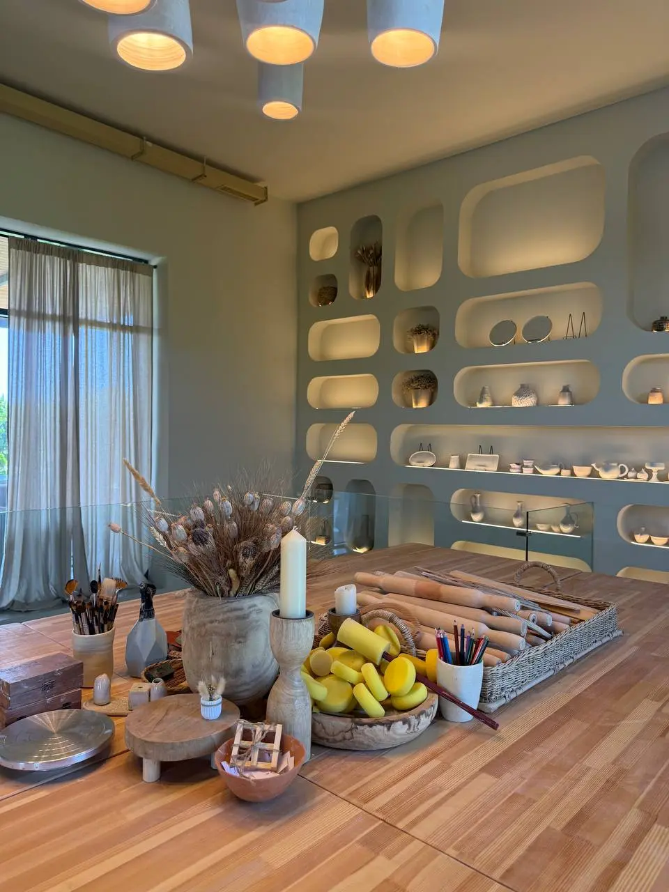 Pottery workspace at Art Village with brushes, rolling pins and dried flowers by the window