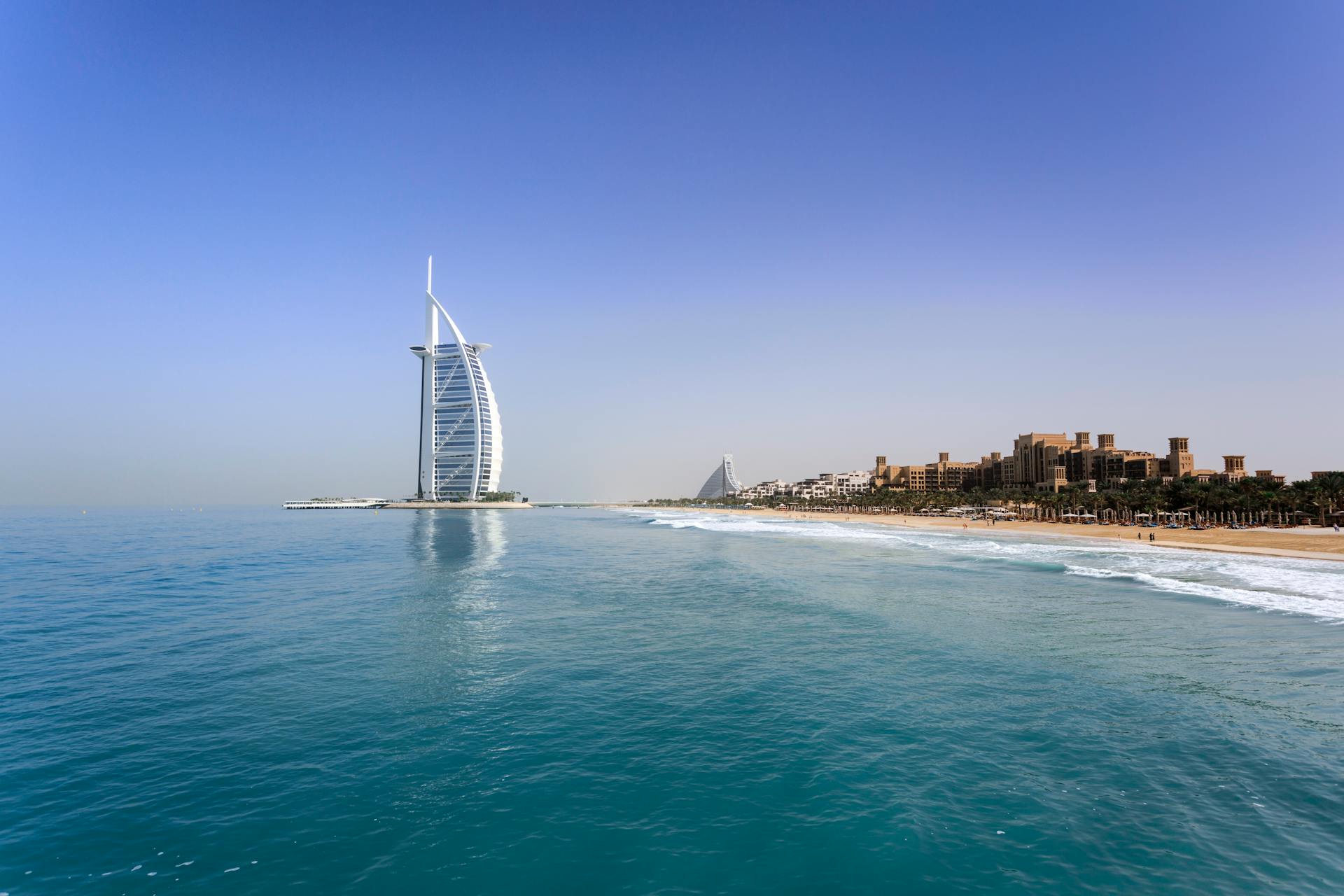 View of Burj Al Arab hotel on Jumeirah Beach with clear blue sky and sandy shore in Dubai