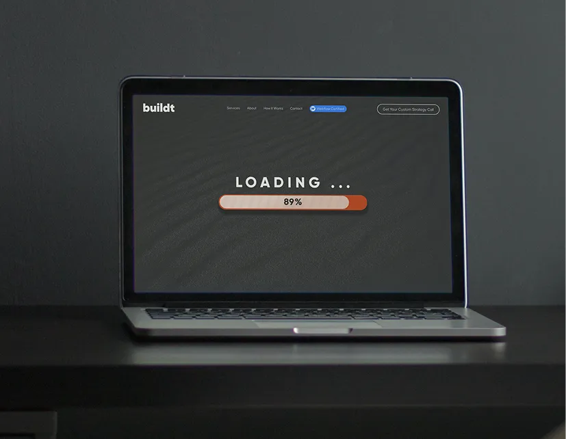 Laptop on a dark surface displaying a loading screen at 89% progress.