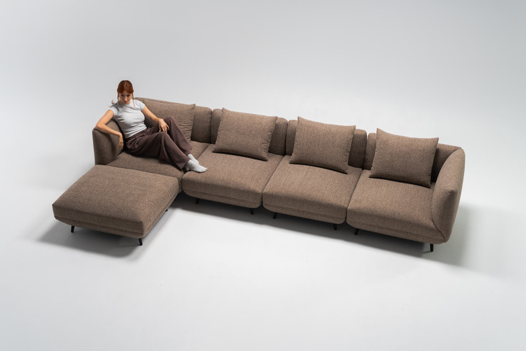 Studio product photo of a modular sofa with a woman sitting on it, shot by Refined for Proferlo Furniture