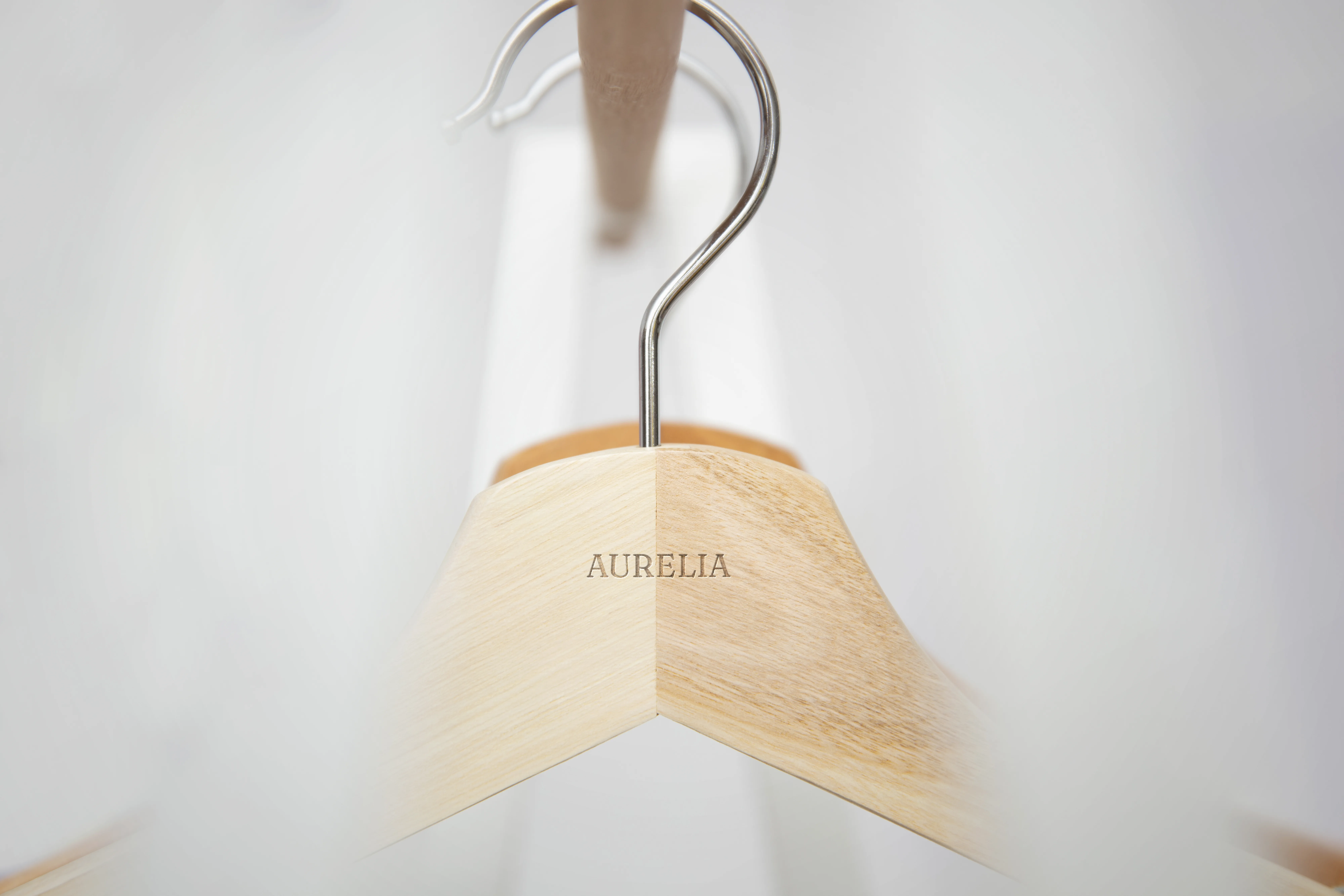 Aurelia branded clothing hanger holding a neutral-toned garment.