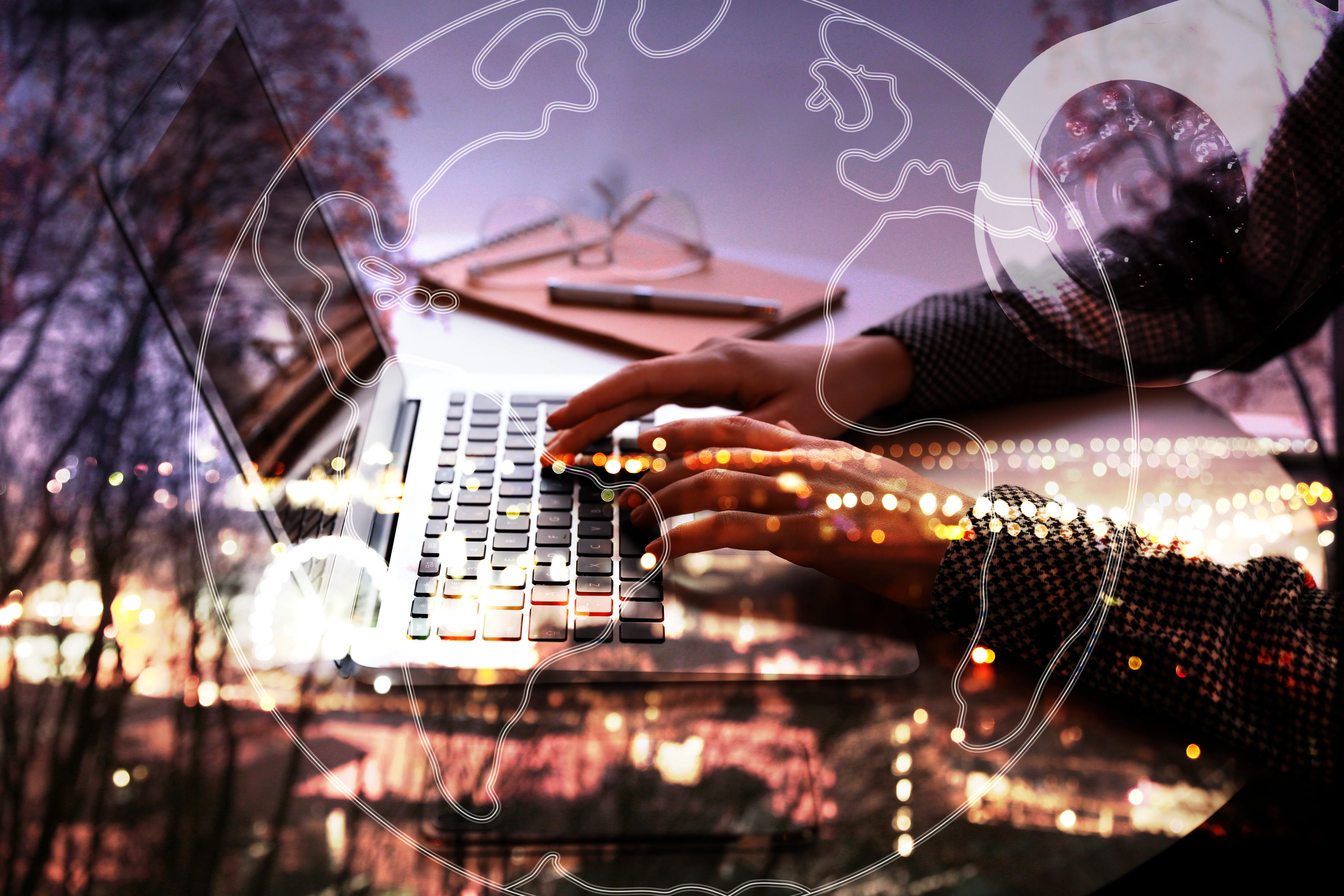 A close-up view of hands typing on a laptop keyboard, with a blurred cityscape and globe overlay in the background, suggesting global connectivity and technology.