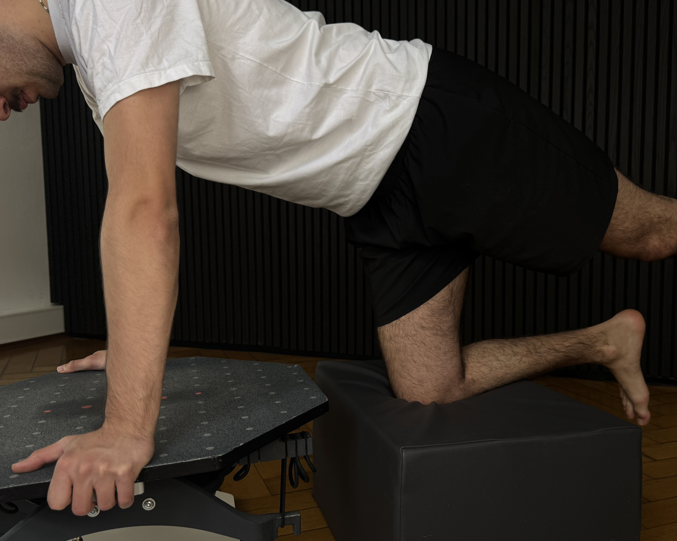 Eine Person im Vierfüßlerstand mit einem Bein in der Luft auf dem neurotrim Gerät.