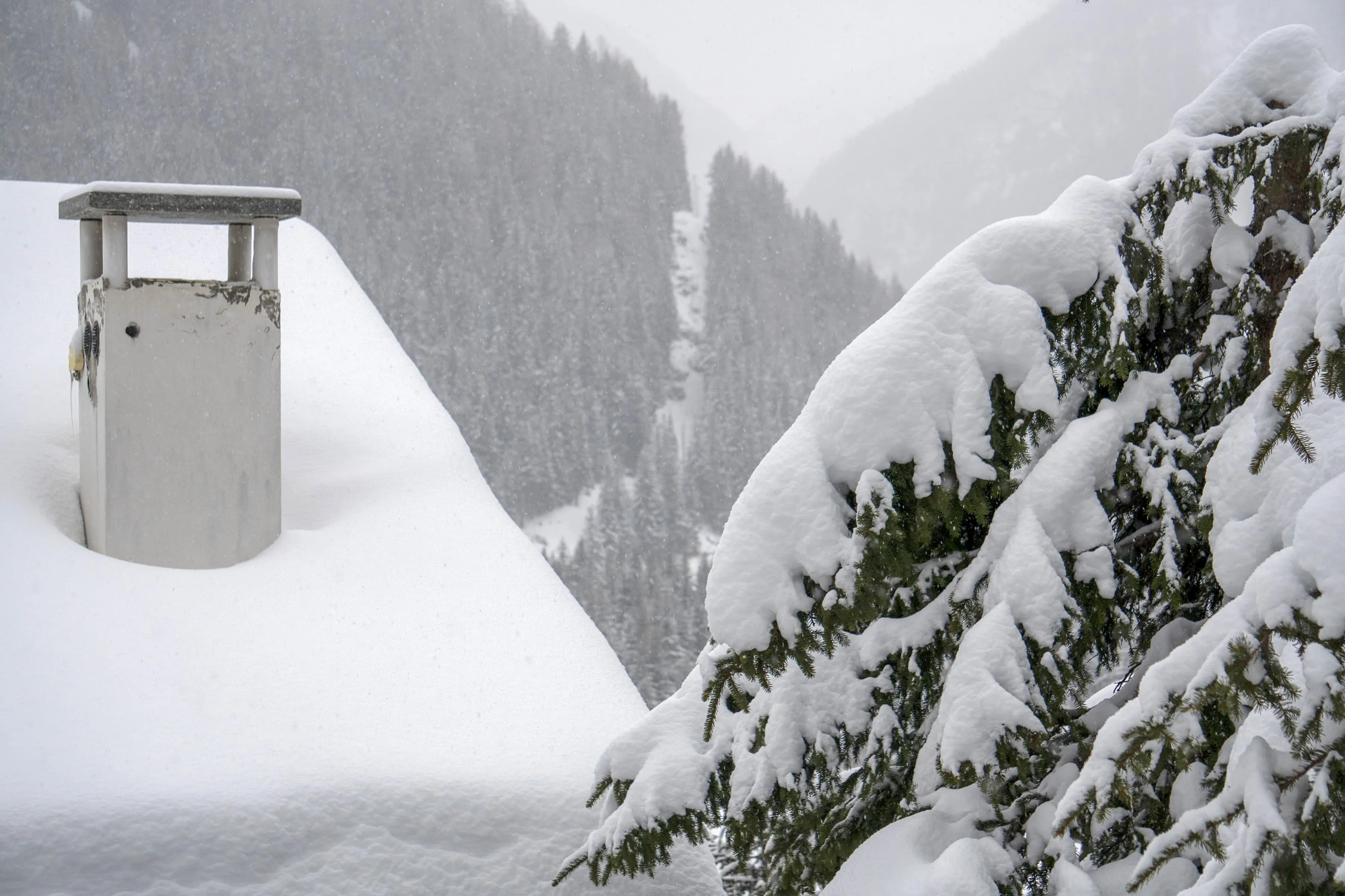 Brick chimney on a residential roof with smoke rising during winter