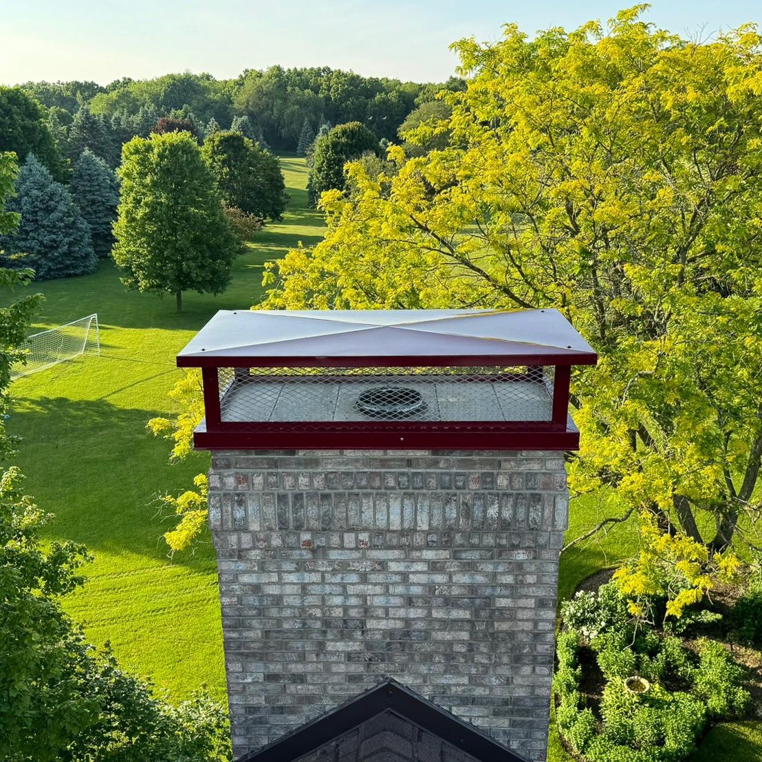 Metal chimney cap being installed on brick chimney