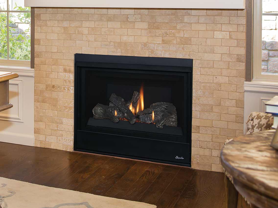 Superior DRT2033 gas fireplace with a black frame and log set in a light brick surround.