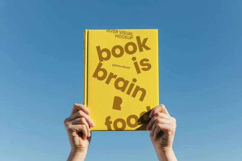 A person holding up a book that says book is brain food.