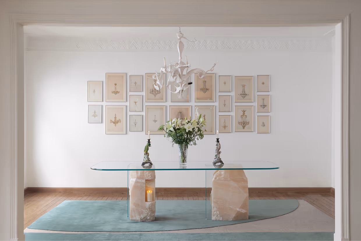 Tension Studies dining table by Liana Yaroslavsky in white onyx and tempered glass, photographed in a Parisian-style interior with vintage chandelier drawings on the wall