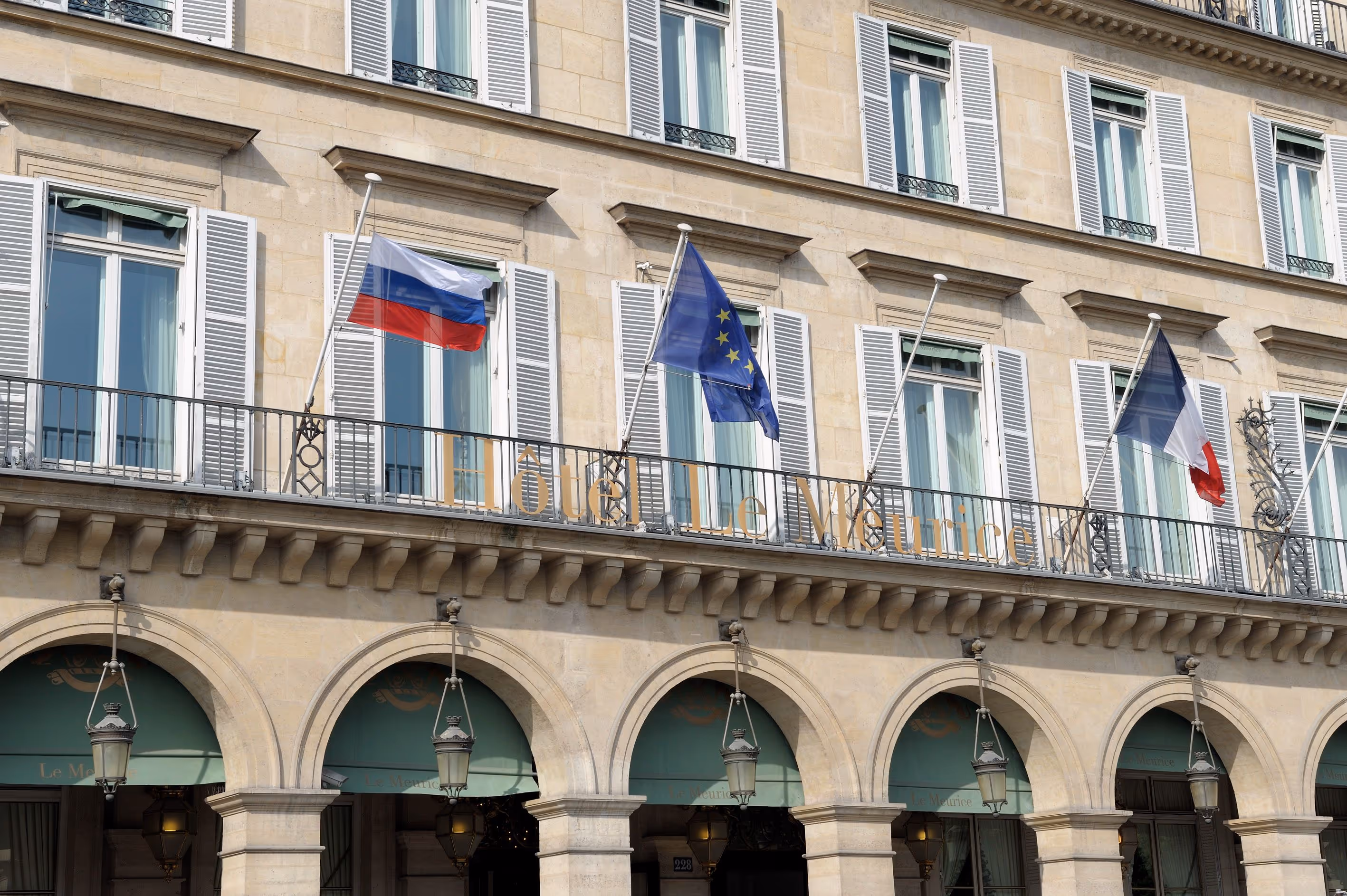 Facade of Hôtel Le Meurice with Russian, European Union, and French flags displayed above arched entrances.