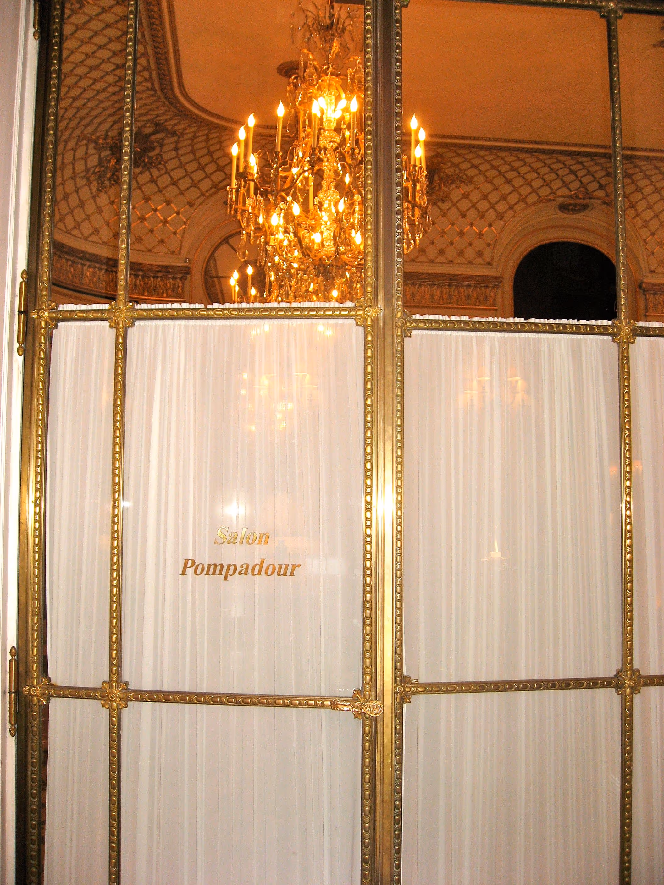 Ornate gold-framed glass doors with white curtains and a chandelier reflected above, labeled Salon Pompadour.